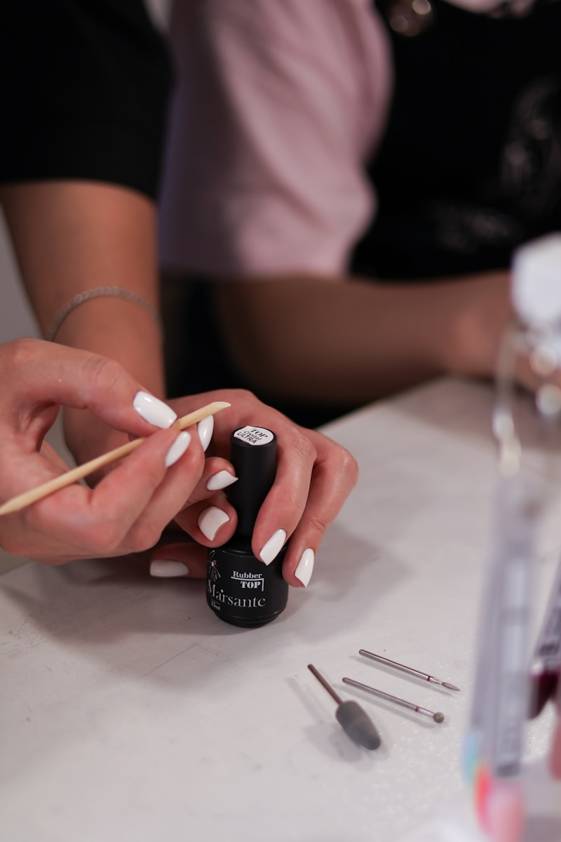 a woman is holding a black nail polish bottle