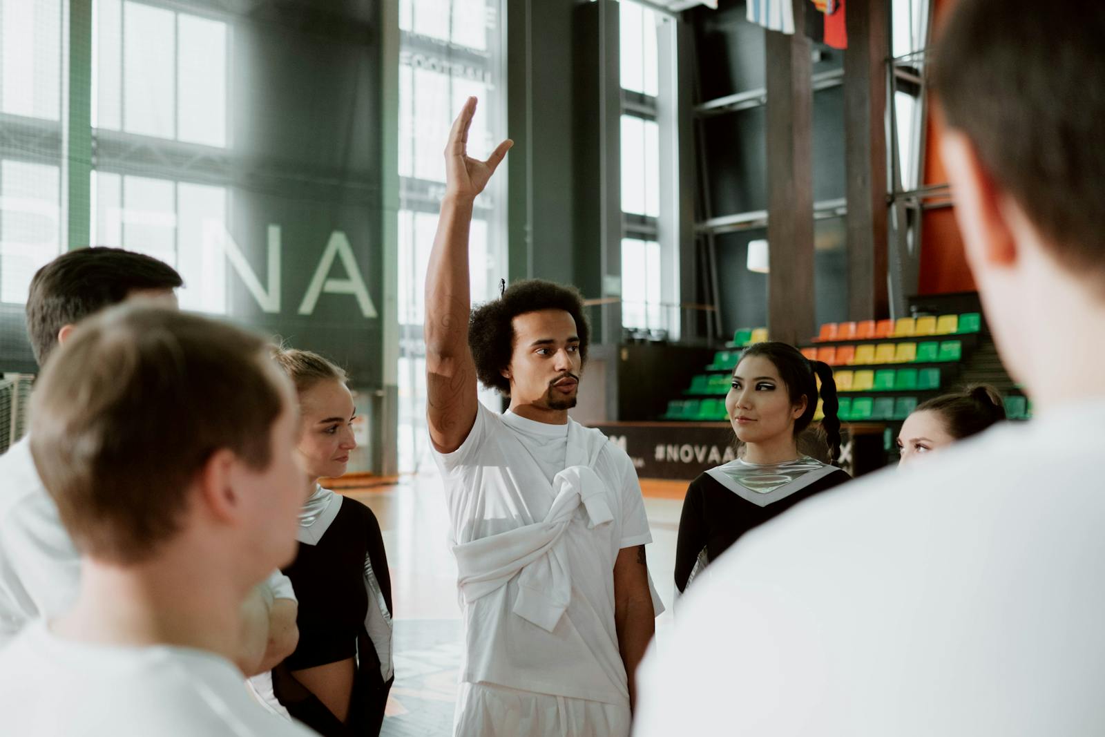 Cheerleading coach instructing a diverse team during practice indoors.
